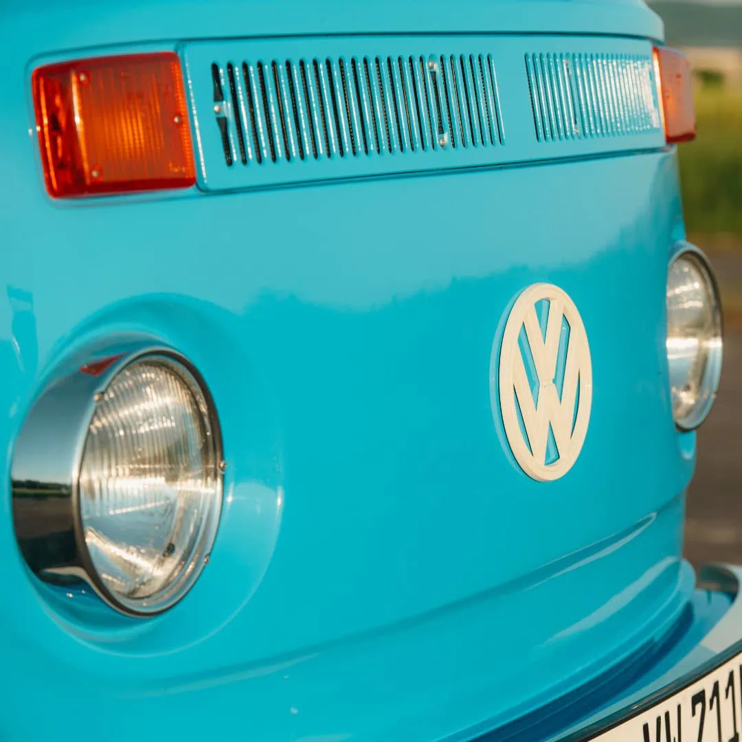Nahaufnahme der Front des blauen VW T2 Fotobus mit VW-Logo und Scheinwerfern.