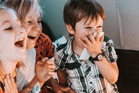 Drei Kinder lachen zusammen im Fotobus bei einem Kindergeburtstag.