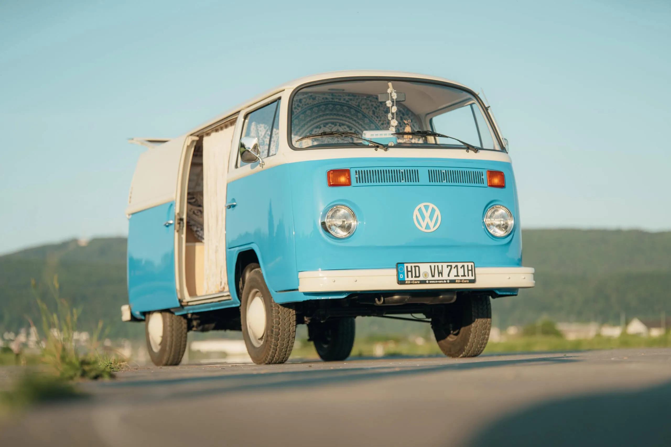 Fotobus Bernd: blau-weißer VW T2 Oldtimer-Bulli mit offener Seitentür an einem sonnigen Tag.